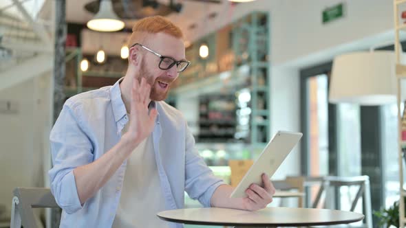 Redhead Man Doing Video Chat on Tablet in Cafe 