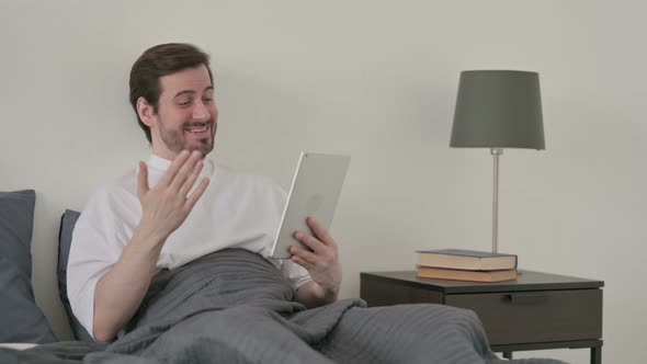 Young Man Doing Video Call on Tablet in Bed
