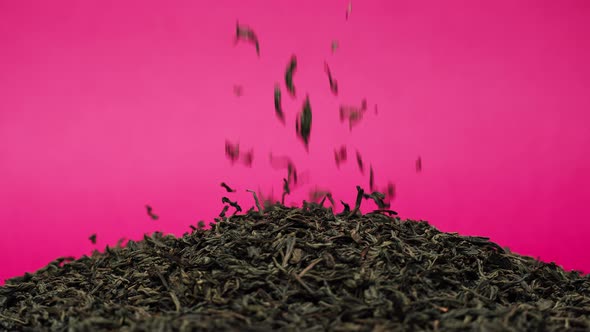 Closeup of Falling Down Dried Tea Leaves on Table on Pink Background