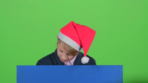 Teenager in the Hat Appears From a Board on a Green Screen