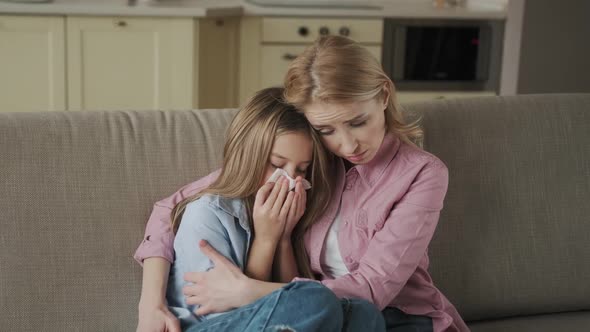 Caucasian Mother Hugging Her Daughter While Sneezing in Tissue Under Blanket at Home