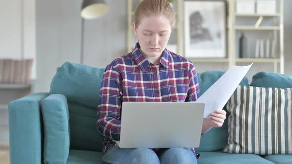 Young Woman Reading Documents While Sitting on Couch