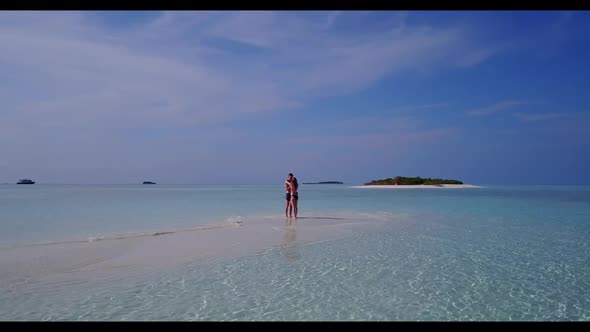 Family of two posing on marine seashore beach vacation by transparent lagoon with white sand backgro