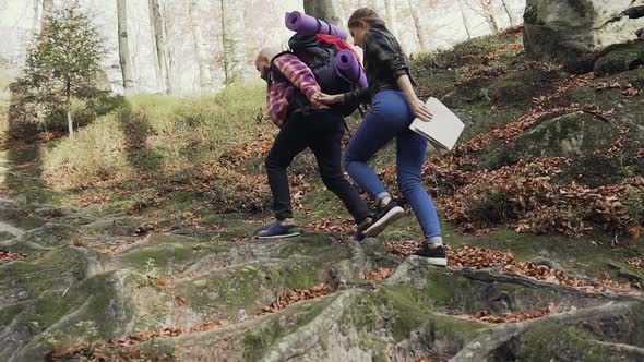 Tourist Man and Woman Climb a High Path to Mountains