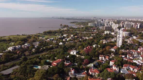 Aerial flyover San Isidro residential area in Buenos Aires with trees and river in background during