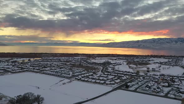 Aerial view flying backwards over snow covered urban city landscape at sunset