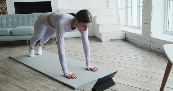 Athletic Young Woman Watching Video Tutorial on Tablet Doing Exercises