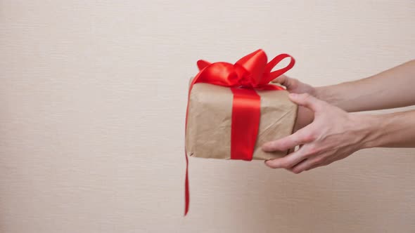 Man Giving a Woman a Gift Wrapped in Kraft Paper and Tied with a Red Ribbon