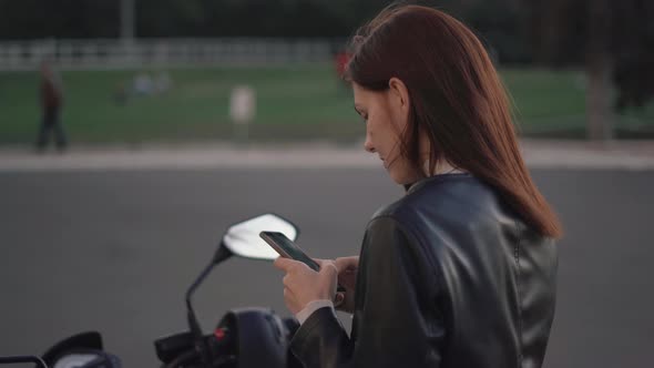 Beautiful Young Redhaired Woman Motorcyclist in a Leather Jacket on Bike