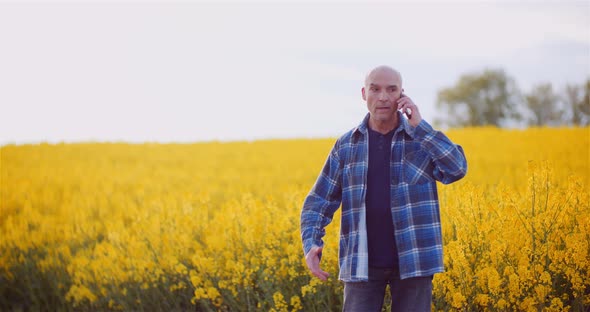 Angry Male Agronomist Talking Through Cellphone On Rapeseed Field