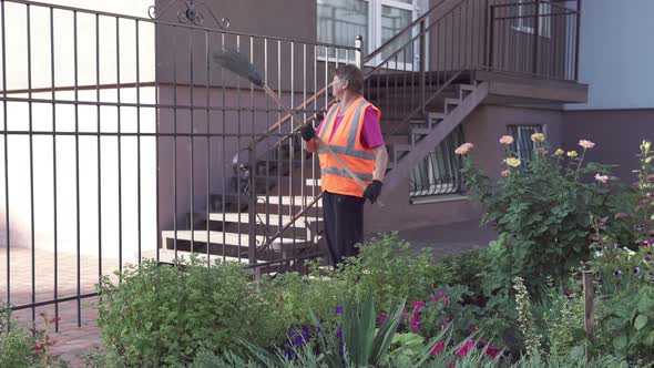 Street janitor picks up garbage. Cleanliness and order in the yard depends on the janitor.