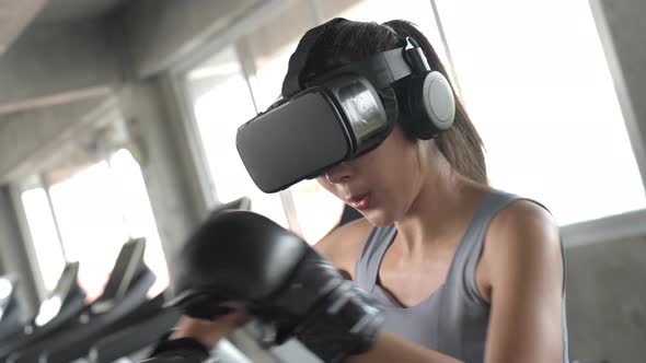 4K Asian sportswoman wearing VR glasses do boxing exercise workout at fitness gym.