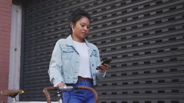 Mixed race woman walking next to her bike on the street