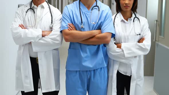 Portrait of doctors standing with arms crossed in corridor