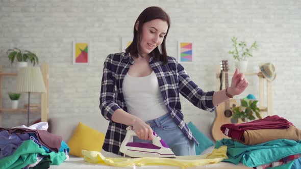 Cheerful Young Woman in Plaid Shirt Ironed Linen Iron at Home Dancing