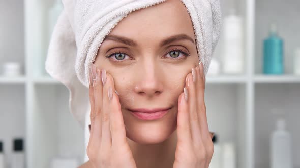 Closeup Face of Smiling Woman Applying Cream on Skin