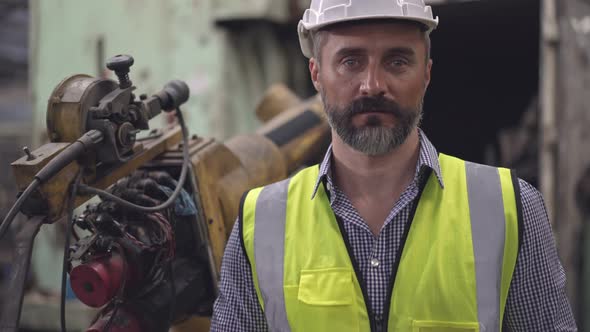 Portrait of male engineer in safety clothing holding digital tablet looking at camera