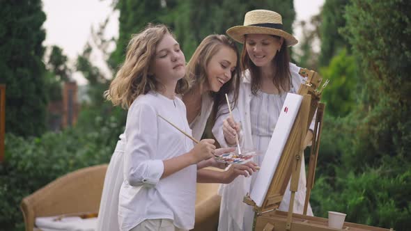 Rack Focus From Joyful Pregnant Woman Enjoying Hobby to Teenage Girl Painting on Easel in Slow