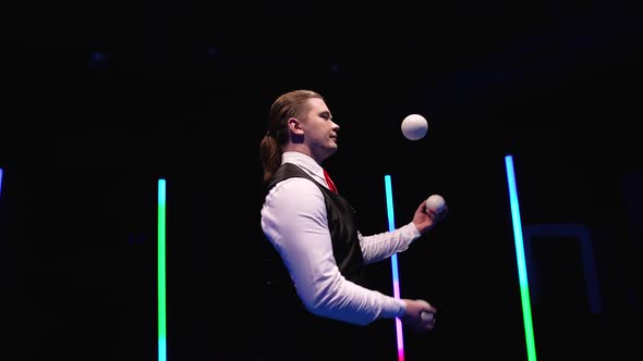 Circle Movement Camera Around Professional Circus Performer Juggling White Balls Against a Black