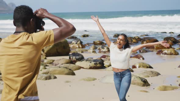 African american man taking photo of his wife with digital camera at the beach