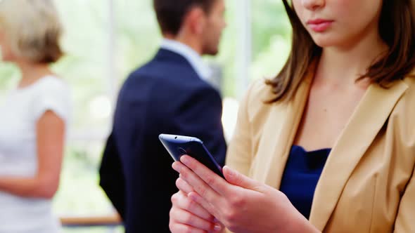 Female business executive text messaging on mobile phone