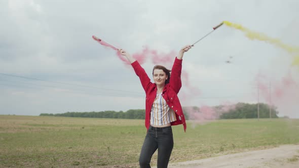 Happy Woman Dancing with Smoking Torches Outdoors