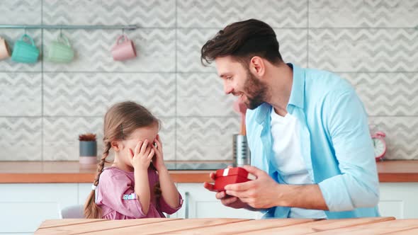 A young single dad giving a present to his little daughter