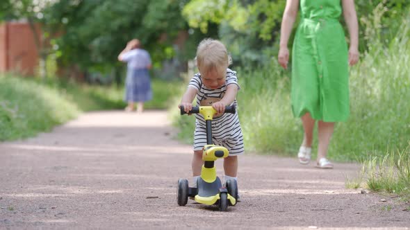 Mother Teaches Her Toddler to Ride Balance Bike for Younger Kids Outdoors 1