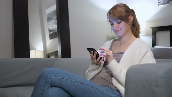 Woman Browsing Internet on Smartphone, Sitting on Couch