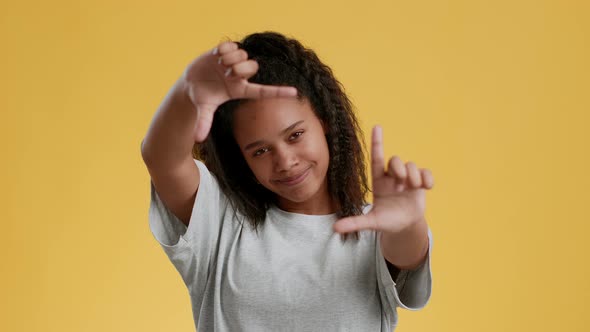 Smiling Teen African American Girl Making Frame with Fingers and Looking to Camera Searching for