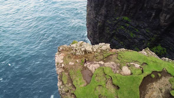 Aerial view of woman walking on the edge of tourists English Slave cliff.