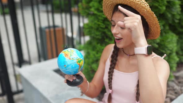Beautiful Young Woman Holds a Small Globe in Her Hands