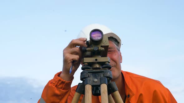 Concentrated Surveyor Looks Through Theodolite and Writes