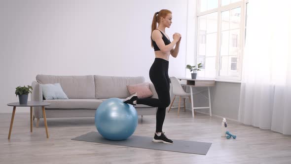 Sporty Woman Doing OneLegged Squats With Fitball Exercising At Home