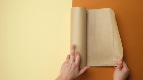 female hands hold roll of brown parchment paper on brown background