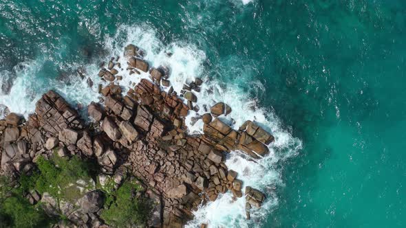 Aerial view of waves crashing into rocky peninsula in Praslin, Seychelles