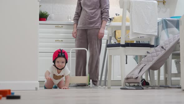 Baby Wearing Safety Helmet Crawling on the Floor 8 Month Old Caucasian Toddler Exploring All Around