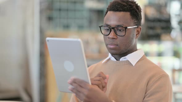 Attractive Creative African Man Using Tablet in Cafe