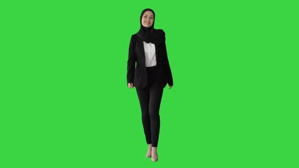 Smiling Islamic Female Model Wearing Hijab Walking and Looking Ahead on a Green Screen, Chroma Key.