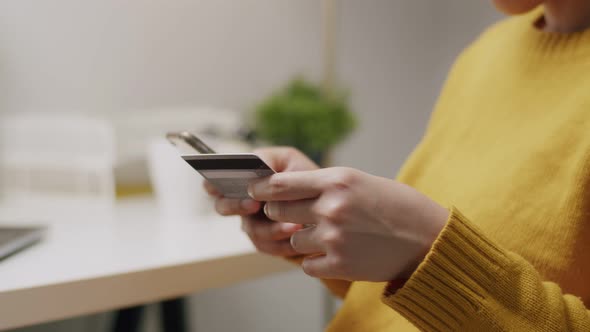 Close-up of an attractive young Asian woman using her cellphone for online shopping.