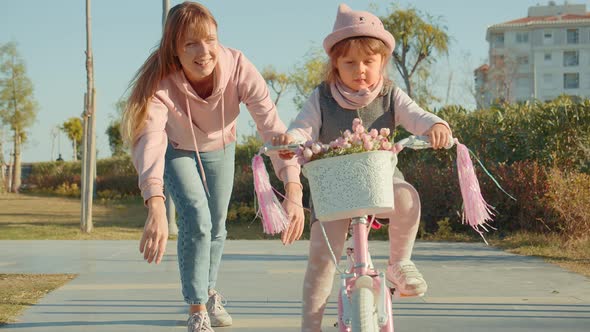 Mother Teaches Her Daughter To Ride A Bike