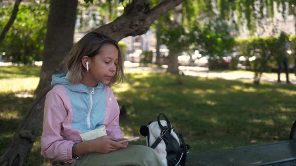 Little Girl Child Kid Sitting on Grass in Park Looking Smart Watch. Smart Watch for Baby Safety