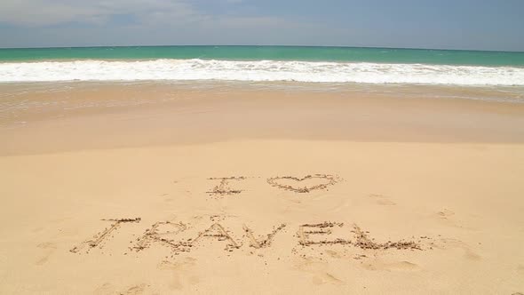 I LOVE TRAVEL written in the beach sand washed aways by waves.