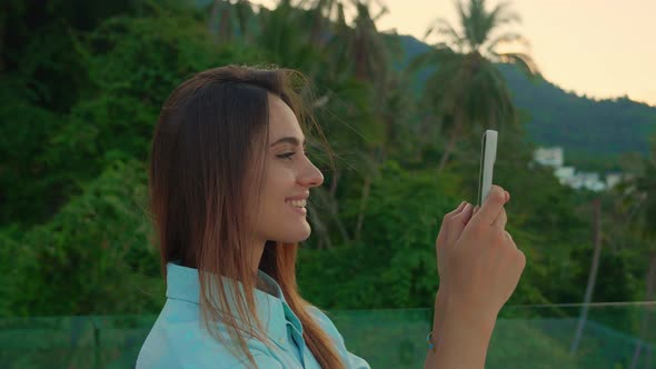 Happy Tourist is Pivoting in One Direction to Take a Panorama of the Topical Forest with Her