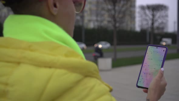 A Woman Uses an Application on Her Smartphone with a Navigator and a Street Map
