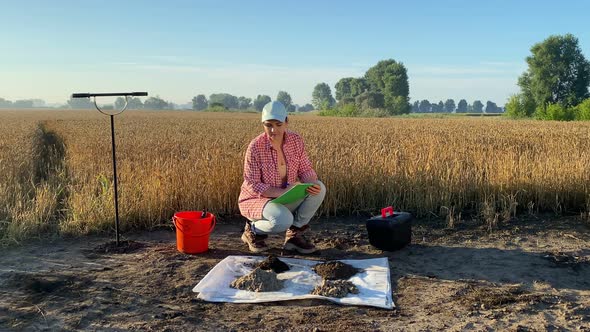Woman Agriculturist Performing Soil Analysis Taking Notes at Field