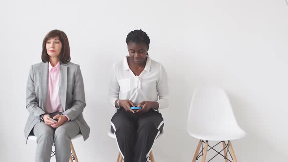 Three Business Ladies Sitting on Chairs Waiting for an Interview for a Senior Position in a Large