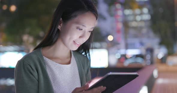 Woman Holding Tablet Computer in City at Night