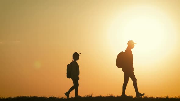 Silhouettes of Father, Mother and Children Hiking. Baby Sits on the Shoulders of His Father. Hiking