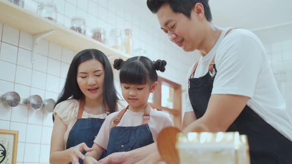 Asian happy family spending time in kitchen together while staying at home doing homemade bakery.